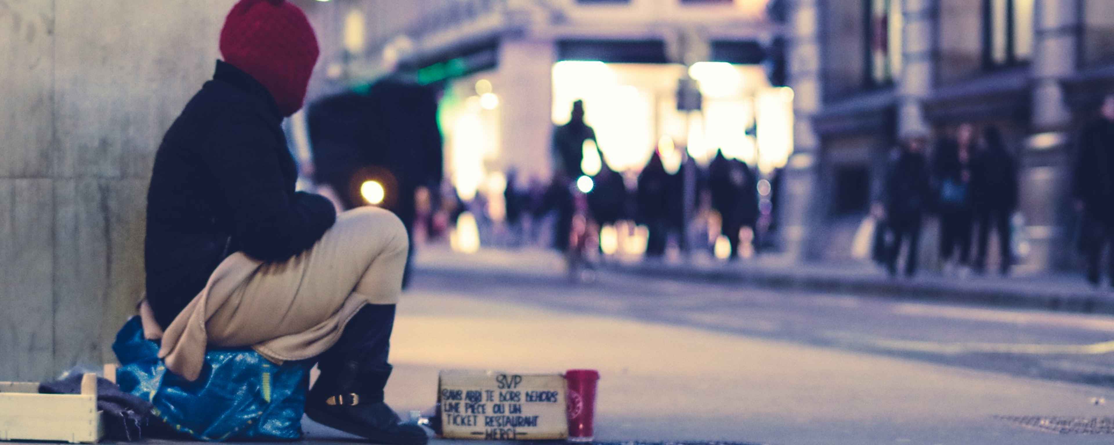 Obdachlose Person sitzt in einer Fußgängerzone